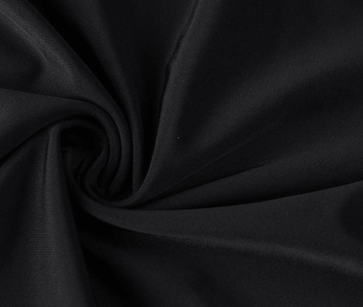 Close-up of black spandex-nylon fabric with a tight swirl pattern, ideal for beach and water sports apparel.